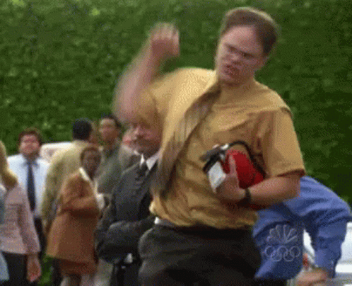 A Man In A Yellow Shirt Is Holding A Red Fire Extinguisher GIF
