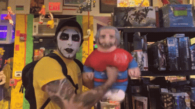 A Man In A Yellow Shirt Is Holding A Stuffed Superman Figure GIF