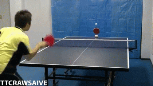 A Man In A Yellow Shirt Is Playing Ping Pong On A Table GIF