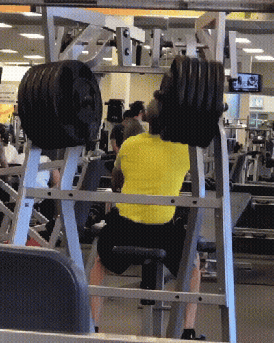 A Man In A Yellow Shirt Is Squatting On A Machine GIF