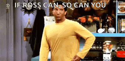 A Man In A Yellow Shirt Is Standing In A Kitchen With His Hand On His Hips . GIF