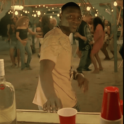 A Man In A Yellow Shirt Is Standing In Front Of A Crowd GIF