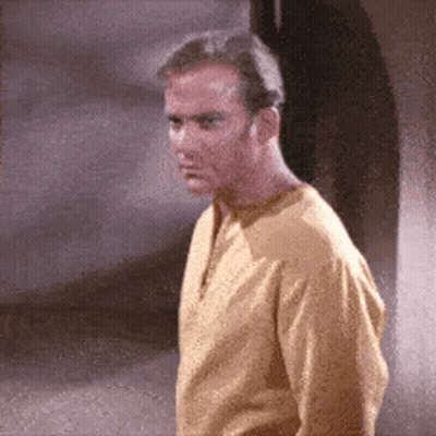 A Man In A Yellow Shirt Is Standing In Front Of A Wall GIF