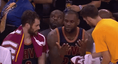 A Man In A Yellow Shirt Is Talking To A Basketball Player In A Cavs Uniform GIF