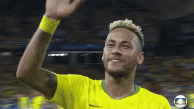 A Man In A Yellow Shirt Is Waving His Hand In The Air GIF