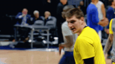 A Man In A Yellow Shirt Stands On A Basketball Court With Other Players GIF