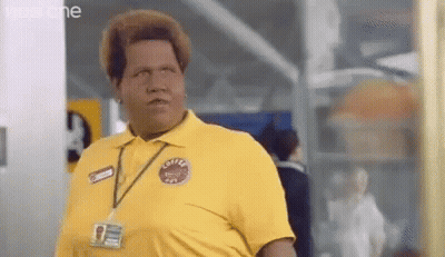 A Man In A Yellow Shirt With A Name Tag Around His Neck Is Standing In A Room . GIF
