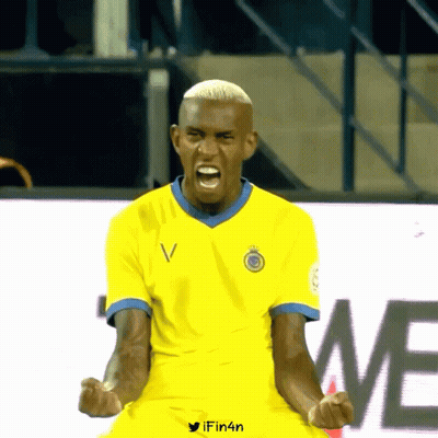 A Man In A Yellow Shirt With The Letter V On The Front GIF