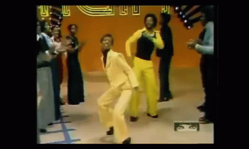A Man In A Yellow Suit Is Dancing In Front Of A Crowd Of People At A Disco . GIF