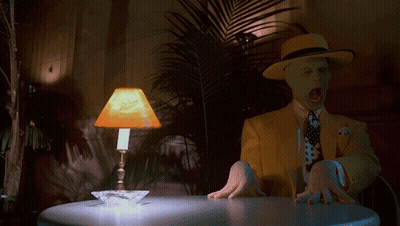 A Man In A Yellow Suit Is Sitting At A Table With A Lamp On It GIF