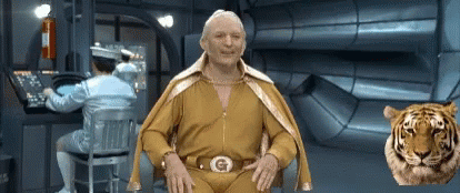 A Man In A Yellow Suit With The Letter G On His Belt Is Sitting In Front Of A Tiger GIF