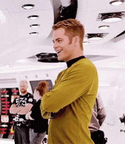 A Man In A Yellow Sweater Is Standing In A Room With His Arms Crossed . GIF
