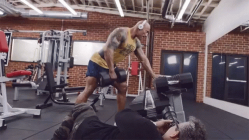 A Man In A Yellow Tank Top That Says " Best Weakest " Is Lifting A Dumbbell In A Gym GIF