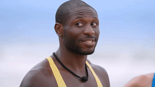 A Man In A Yellow Tank Top With A Black Necklace Around His Neck GIF