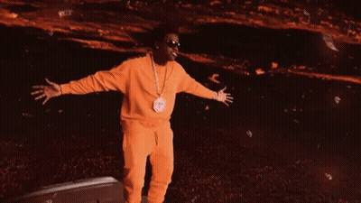 A Man In A Yellow Tracksuit Is Standing In Front Of A Green Background GIF