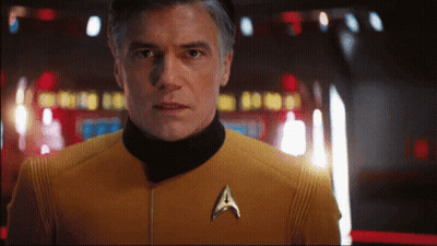 A Man In A Yellow Uniform With A Star Trek Badge GIF