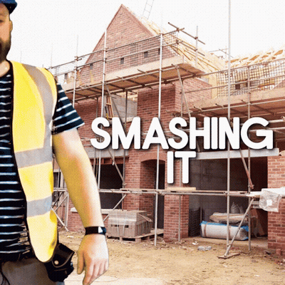 A Man In A Yellow Vest Stands In Front Of A Building Under Construction With The Words Smashing It Behind Him GIF