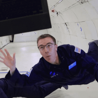 A Man In A Zero G Space Suit Is Floating In The Air GIF
