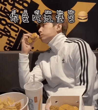 A Man In An Adidas Jacket Is Eating A Hamburger GIF