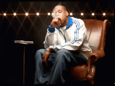 A Man In An Adidas Jacket Sits In A Chair GIF