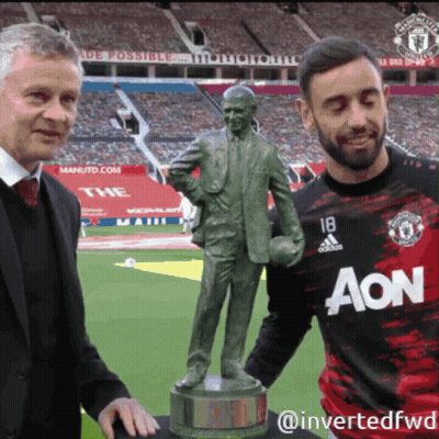 A Man In An Aon Jersey Stands Next To A Man Holding A Statue GIF