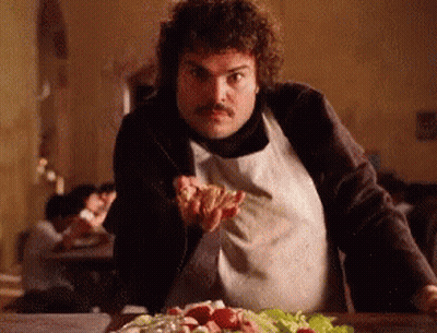 A Man In An Apron Is Holding A Piece Of Pizza In His Hand GIF