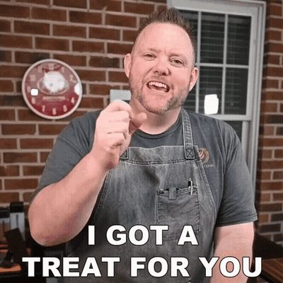 A Man In An Apron Is Pointing At The Camera With The Words I Got A Treat For You Below Him GIF