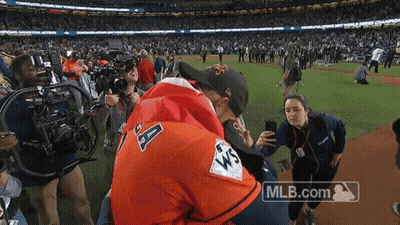 a man in an astros jersey is hugging another man on a baseball field