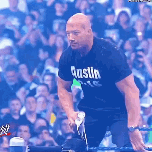 A Man In An Austin T-Shirt Is Standing In Front Of A Crowd Of People . GIF