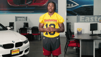 A Man In An Easterns Automotive Group Jersey Stands In Front Of A Bmw GIF