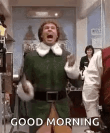 A Man In An Elf Costume Is Screaming And Saying `` Good Morning '' In A Kitchen . GIF