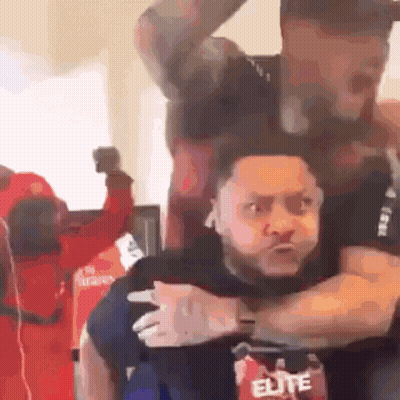 A Man In An Elite Shirt Is Carrying Another Man On His Shoulders GIF