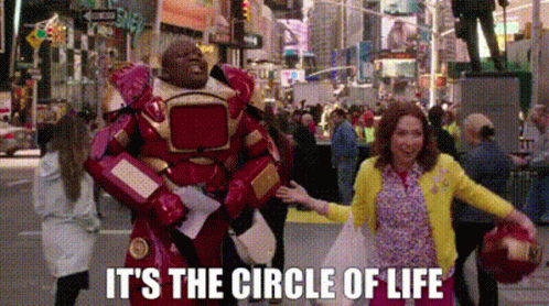 A Man In An Iron Man Costume Is Standing Next To A Woman In A Yellow Sweater . GIF