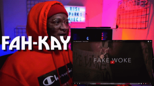 A Man In An Orange Hoodie Is Sitting In Front Of A Computer Screen That Says Fah-Kay GIF