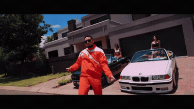 A Man In An Orange Jacket Is Standing In Front Of A Bmw GIF