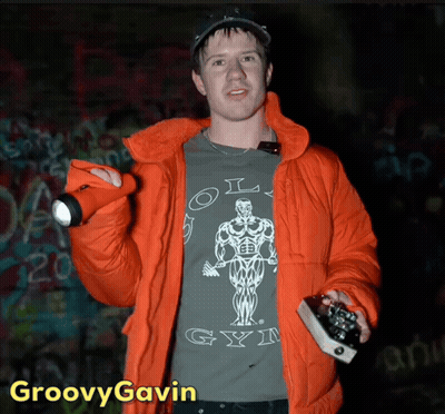 A Man In An Orange Jacket Is Wearing A Shirt That Says Old Gym On It GIF