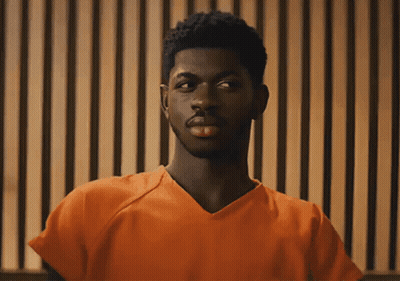A Man In An Orange Prison Uniform Is Looking At The Camera GIF