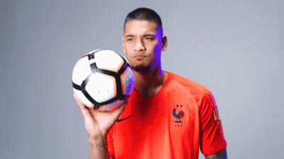 A Man In An Orange Shirt Holds A Soccer Ball In His Hand GIF