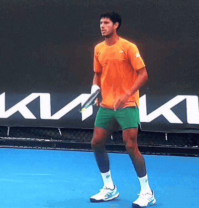 A Man In An Orange Shirt Is Holding A Tennis Racquet GIF