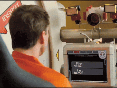 A Man In An Orange Shirt Is Looking At A Screen That Says First Name And Last Name GIF