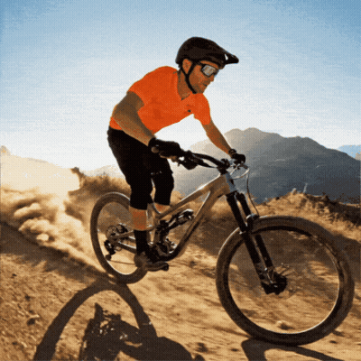 A Man In An Orange Shirt Is Riding A Mountain Bike GIF