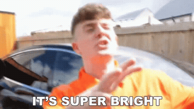 A Man In An Orange Shirt Is Saying It 'S Super Bright . GIF