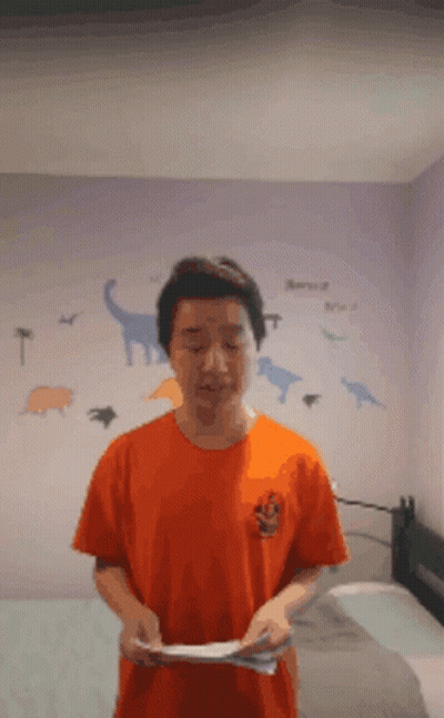 A Man In An Orange Shirt Is Standing In Front Of A Dinosaur Wall Decal GIF