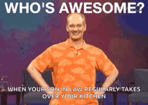 A Man In An Orange Shirt Is Standing With His Hands On His Hips And Says Who 'S Awesome . GIF
