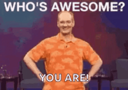 A Man In An Orange Shirt Is Standing With His Hands On His Hips And Says `` Who 'S Awesome ? You Are ! `` GIF