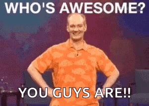 A Man In An Orange Shirt Is Standing With His Hands On His Hips And Says Who 'S Awesome ? You Guys Are GIF