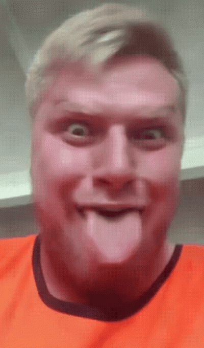 A Man In An Orange Shirt Is Sticking Out His Tongue . GIF