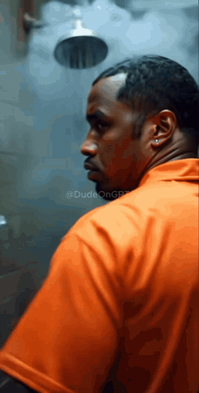 A Man In An Orange Shirt Stands In Front Of A Shower GIF