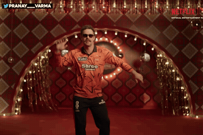A Man In An Orange Shirt That Says Netflix On It GIF