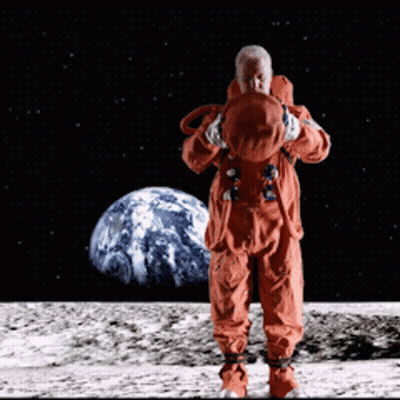 A Man In An Orange Space Suit Stands On The Moon In Front Of The Earth GIF